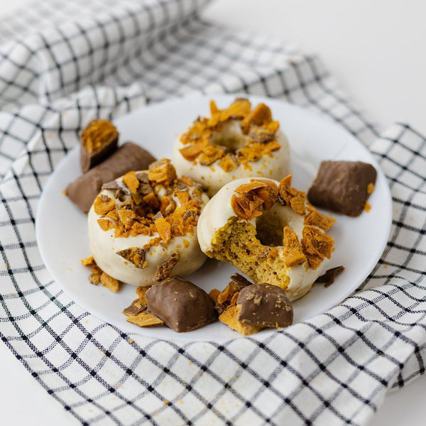3 Butterfinger® Protein Donuts on a plate with pieces of a Butterfinger® candy bar 