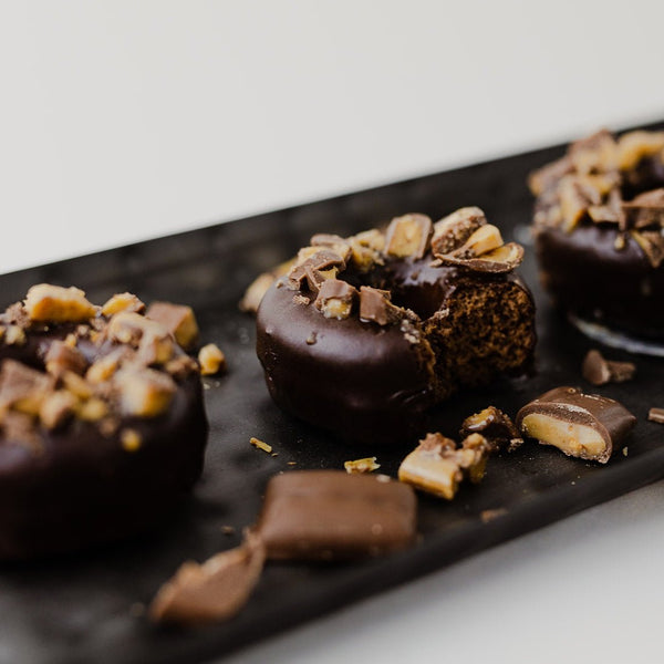 3 Heath Protein Donuts on a tray with Heath® candy bar pieces