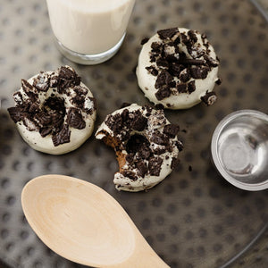 3 Oreo Protein Donuts with a glass of milk & a wooden spoon