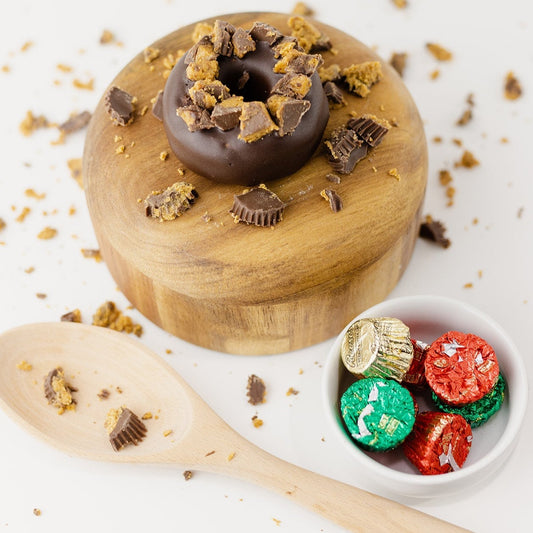 A Reese's® Protein Donut next to a wooden spoon & some PB cups